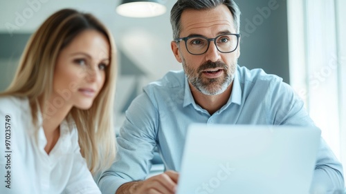 A man and a woman are looking at a laptop together