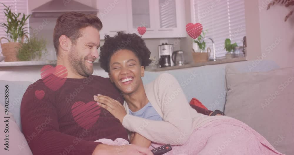 Animation of hearts over diverse couple embracing on sofa and watching tv Animation of hearts over diverse couple embracing on sofa and watching tv