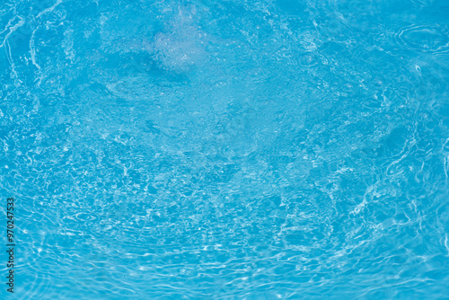 Blue water with ripples on the surface. Defocus blurred transparent blue colored clear calm water surface texture with splashes and bubbles. Water waves with shining pattern texture background.