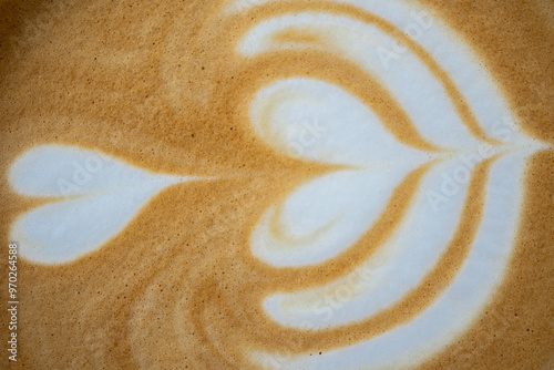 A beautiful macro photograph capturing the intricate and artistic rosetta heart pattern in creamy latte art on a fresh cup of coffee.