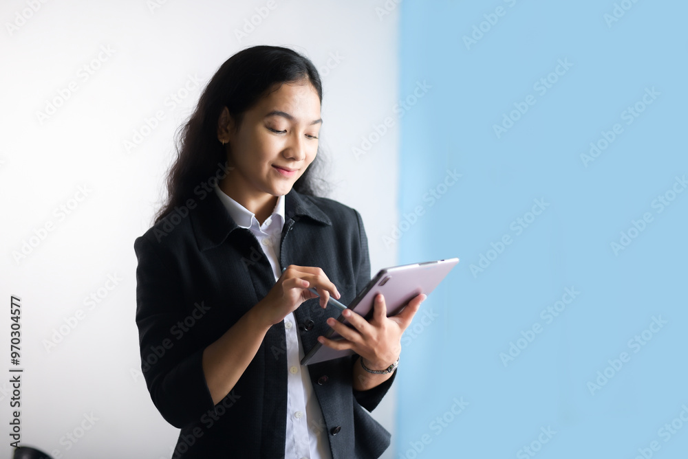 Portrait of attractive Asian businesswoman standing holding tablet isolated on white and blue backround Portrait of attractive Asian businesswoman standing holding tablet isolated on white and blue backround