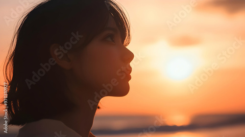 At a Sunset Beach: A Japanese woman gazing out at the ocean as the sun sets