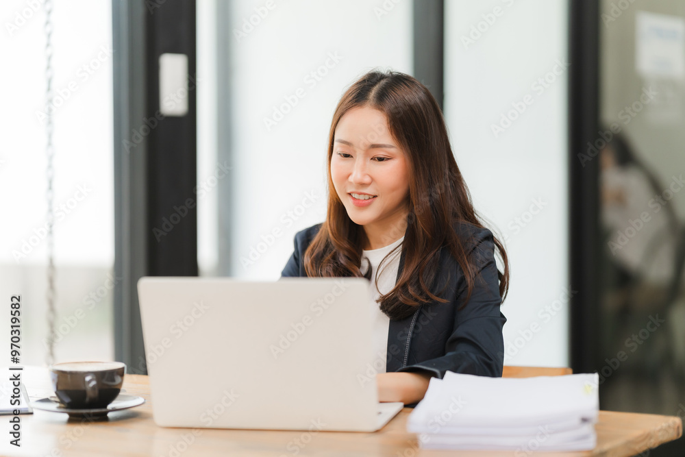 Focused Professional Grace: A young Asian businesswoman exudes quiet confidence as she efficiently tackles her workload on a laptop, embodying modern professionalism in a bright office setting. Focused Professional Grace: A young Asian businesswoman exudes quiet confidence as she efficiently tackles her workload on a laptop, embodying modern professionalism in a bright office setting.