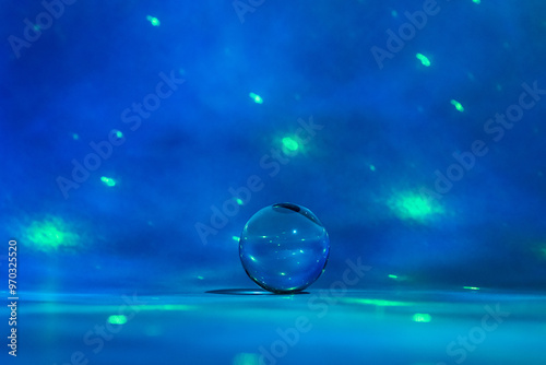Glass ball surrounded by shades of blue with green light spots.