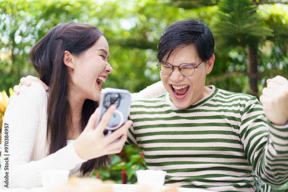 Excited Asian man and woman expressing their happy and satisfied emotion after got a message on smartphone. Excited Asian man and woman expressing their happy and satisfied emotion after got a message on smartphone.
