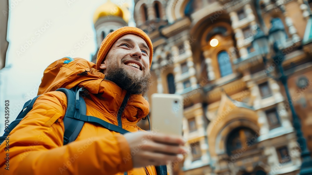 A joyful traveler smiling while using a smartphone in a vibrant orange jacket against a historical building backdrop. A joyful traveler smiling while using a smartphone in a vibrant orange jacket against a historical building backdrop.