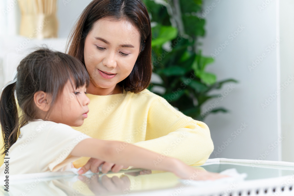 Asian mother enjoying with daughter at home, Mom and kid girl cleaning table in living room Asian mother enjoying with daughter at home, Mom and kid girl cleaning table in living room