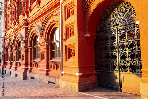The facade of the Historical Museum building in Moscow with forged gates at sunset.