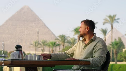 A Man With Beard On A Restaurant With Overlooking Views Of The Great Pyramids In Giza, Egypt. Static Shot photo