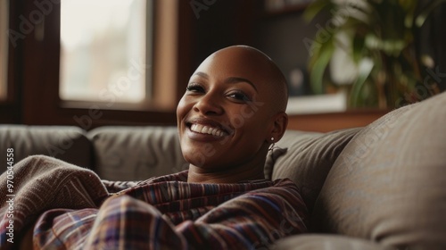 Happy beautiful black lesbian bald woman sitting on a couch at home