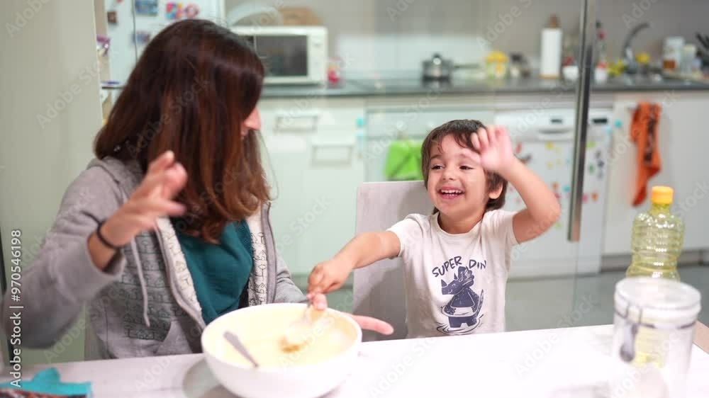 A woman and a child are making a cake together. The child is wearing a shirt that says A woman and a child are making a cake together. The child is wearing a shirt that says