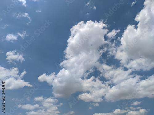 A vast expanse of sky, painted in the softest hues of blue, is adorned with fluffy white clouds. The gentle contrast between the deep blue and the bright white creates a serene and calming image. photo