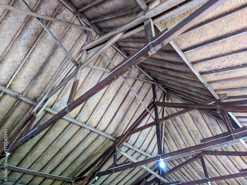 Looking up from below, the intricate wooden beams of the roof form a precise, geometric pattern. The warm, natural tones of the wood contrast with the shadows, creating a sense of depth and craftsmans photo