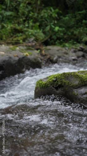 Corriente de río bajando por la montaña rodeado de mucha vegetación y rocas en el bosque tropical en cámara lenta