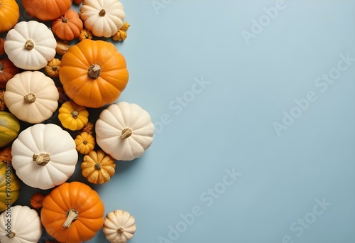 Assorted pumpkins and gourds in various shapes, sizes, and colors including orange, yellow, and white, arranged on a light blue background.