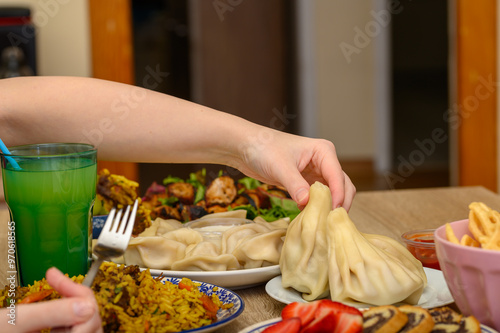 Pyszna kolacja, kuchnia gruzińska. Dziewczyna sięga ręka po pierogi himkali  photo