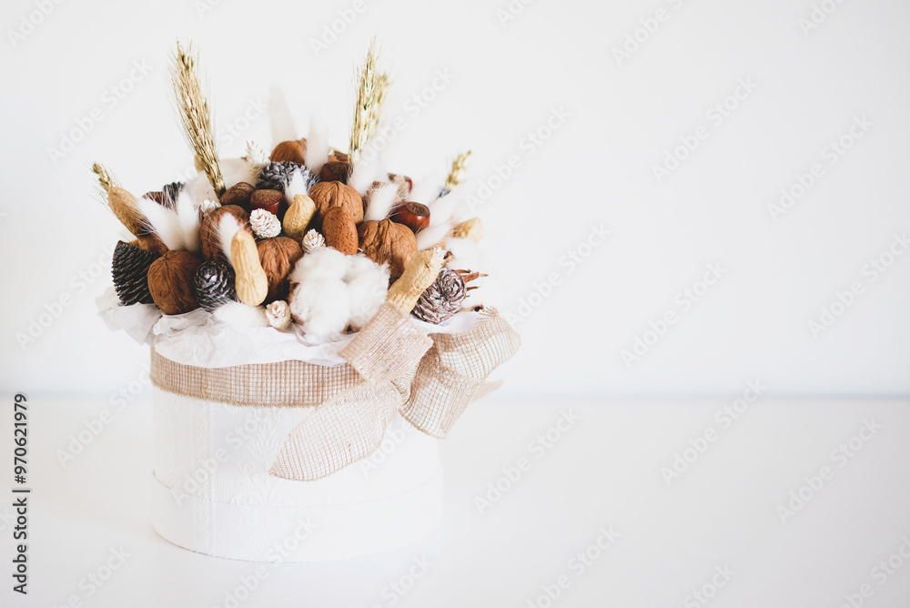 Beautiful handmade Christmas bouquet of nuts, pinecones and cotton flowers in round gift box against white background. Holiday floral decor. Copy space for text. Beautiful handmade Christmas bouquet of nuts, pinecones and cotton flowers in round gift box against white background. Holiday floral decor. Copy space for text.