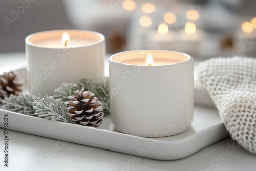 Lit candles in glass holders surrounded by pinecones and evergreen branches