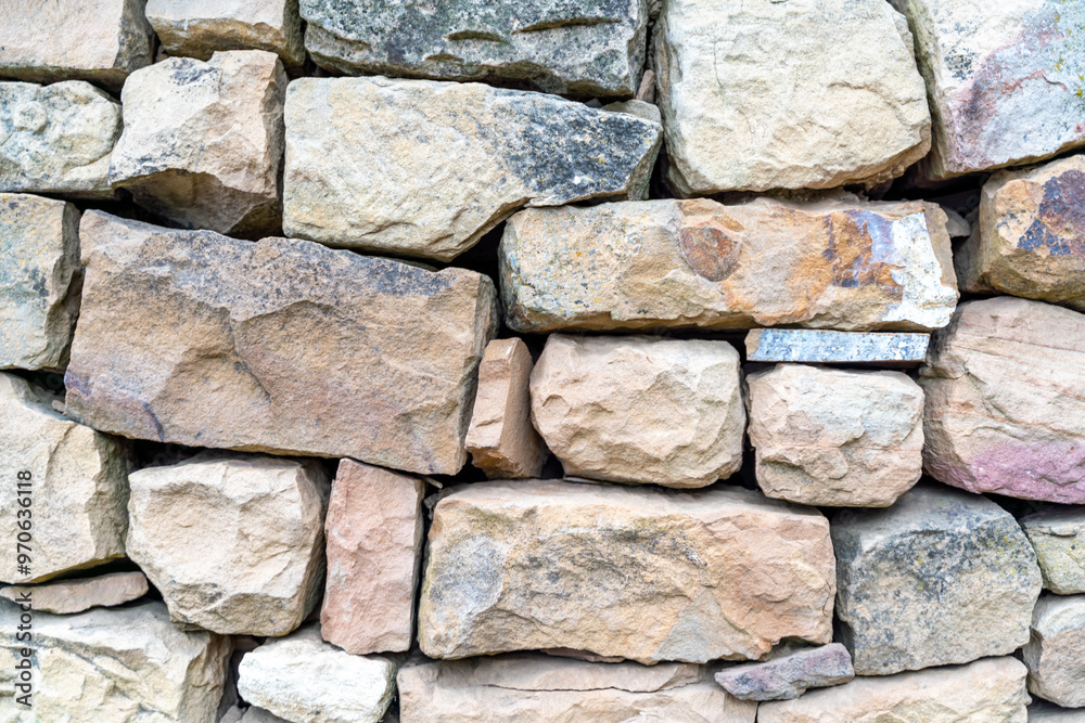 A wall made of stone blocks with a rough texture. The wall is brown and gray in color. A wall made of stone blocks with a rough texture. The wall is brown and gray in color.