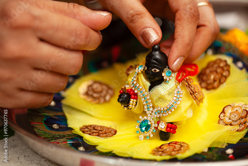 An Indian woman adorns (Laddu Gopal), a Hindu god 'Krishna', after performing a ceremonial bath during the Krishna Janmashtami festival. photo