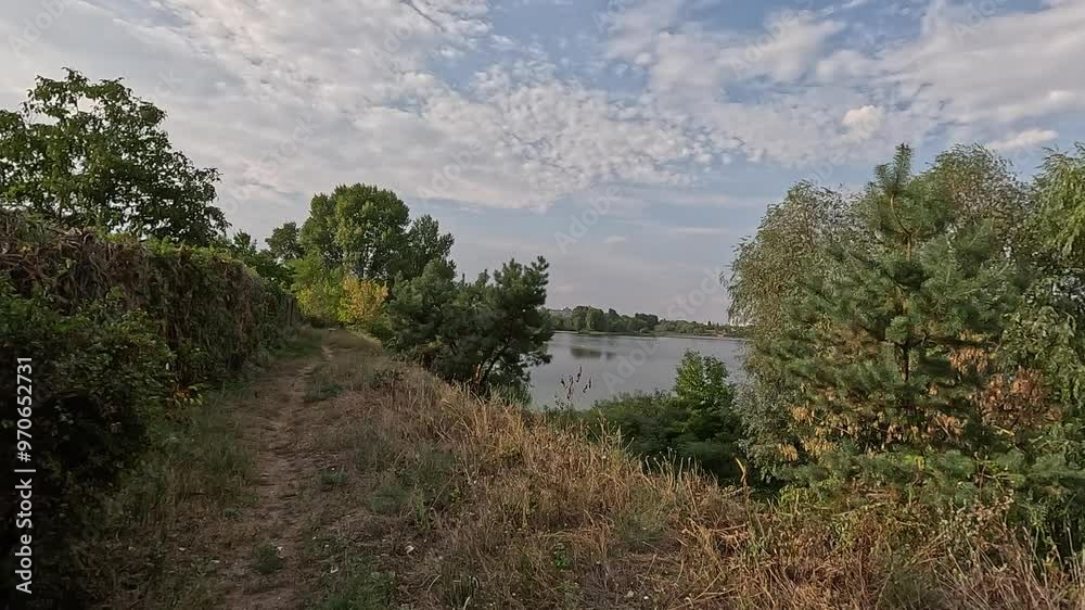 Walking along the path in autumn. Autumn landscape. Autumn leaves on the ground. Narrow path. Hiking by the river. Lake and sky. Beautiful natural landscape. HDR video 4K 60 fps. Walking along the path in autumn. Autumn landscape. Autumn leaves on the ground. Narrow path. Hiking by the river. Lake and sky. Beautiful natural landscape. HDR video 4K 60 fps.
