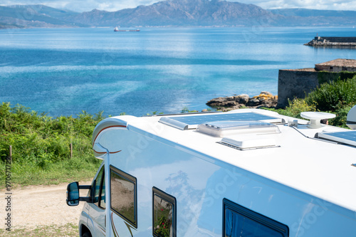 Campervan in camp parking near beach at coastline. Family rv camper van vehicle at seaside. Rving motorhome lifestyle travel to sea. Travel on Campervan along Spain coast. Caravaning Parking. Camping