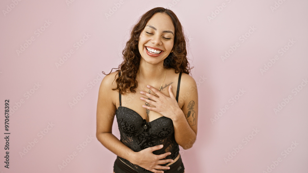 Laughing young adult woman with tattoos, wearing black, isolated against a pink background. Laughing young adult woman with tattoos, wearing black, isolated against a pink background.