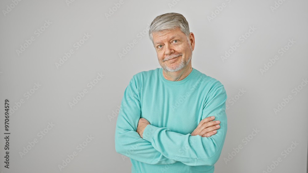 A middle-aged man with grey hair and a turquoise sweater stands arms crossed against a white background, exuding confidence and maturity. A middle-aged man with grey hair and a turquoise sweater stands arms crossed against a white background, exuding confidence and maturity.