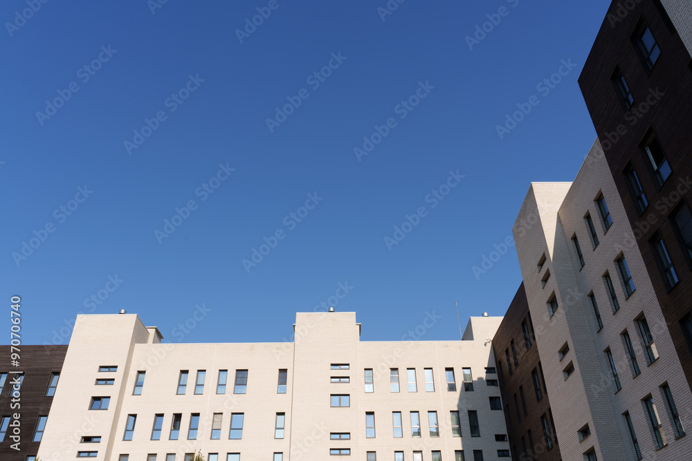 Obraz premium A low-angle view of modern apartment buildings against a clear blue sky.
