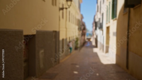 Blurred street in mallorca featuring a defocused person walking in an outdoor setting under bright sunlight.