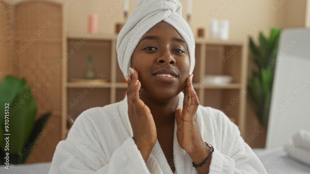 Young, african, american, woman enjoying a spa treatment indoors, wearing a white robe and head towel, while seated in a tranquil wellness center.