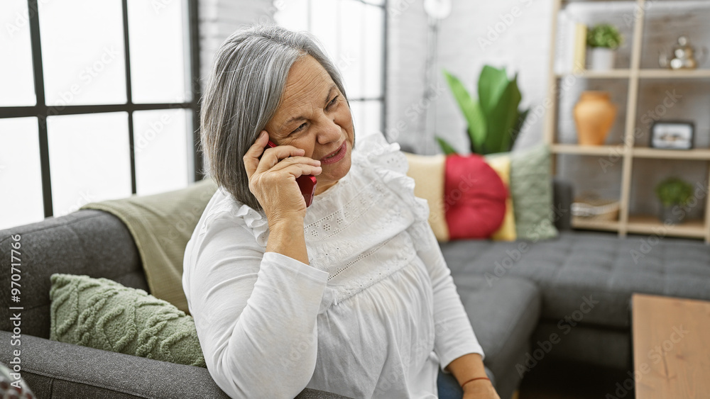 Senior woman smiling during a casual phone call at home, showcasing a comfortable lifestyle and connection. Senior woman smiling during a casual phone call at home, showcasing a comfortable lifestyle and connection.