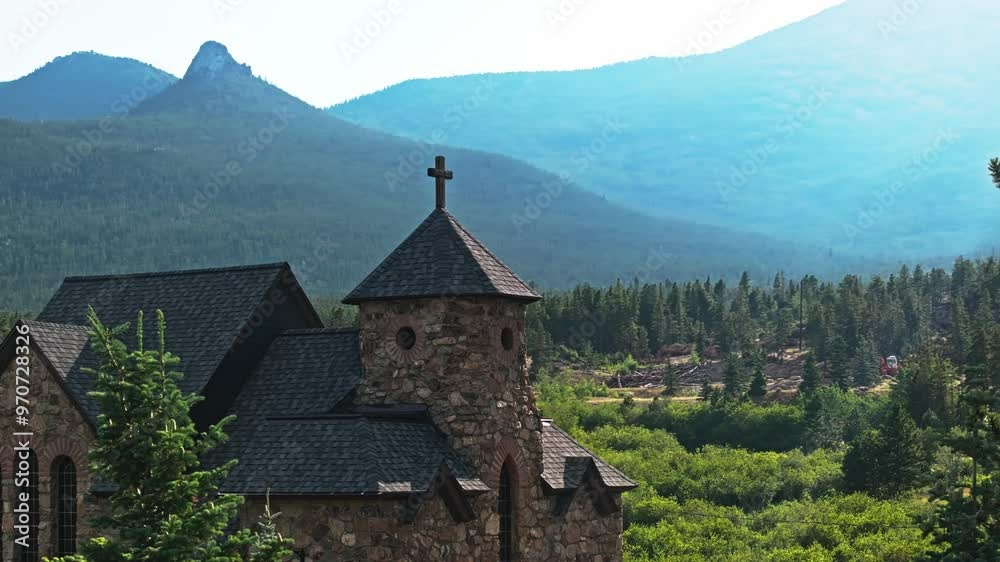 Aerial orbit reveal past evergreen trees with stone cross on top of picturesque chapel in Colorado mountains Aerial orbit reveal past evergreen trees with stone cross on top of picturesque chapel in Colorado mountains