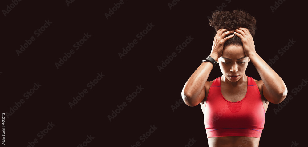 Portrait of concentrated athletic african woman in sportswear touching her head over black background Portrait of concentrated athletic african woman in sportswear touching her head over black background