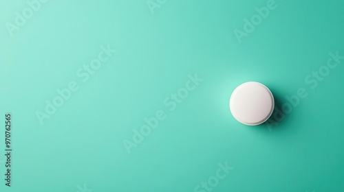 Single vitamin tablet placed in the center of a pastel green background, minimalist design, top view