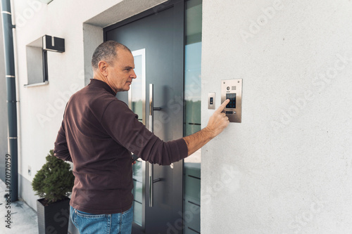 Fotografía A man pressing a doorbell intercom at the entrance of a modern building