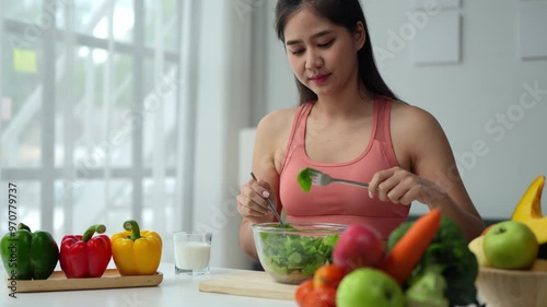 Beautiful young woman in sportswear preparing vegetable salad Fruits to eat after exercise in living room with sofa, healthy life concept, nutrition and dieting lifestyle of life.