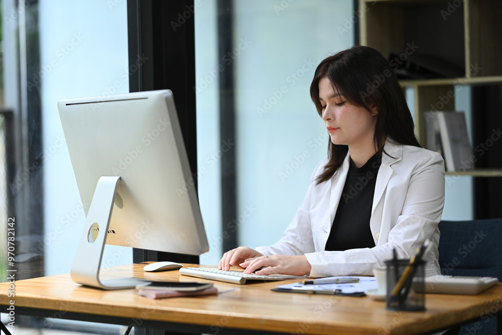 Focused female entrepreneur working with financial data at office desk Focused female entrepreneur working with financial data at office desk