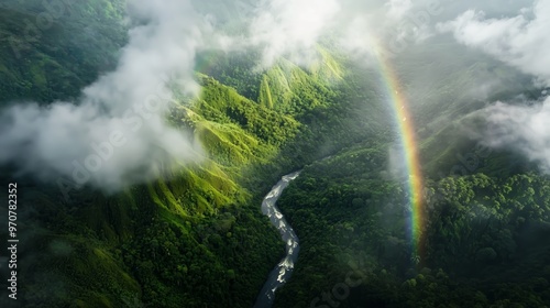 This image showcases a stunning aerial view of a vibrant rainbow arching over a lush, green valley. A winding river meanders through the dense forested landscape.