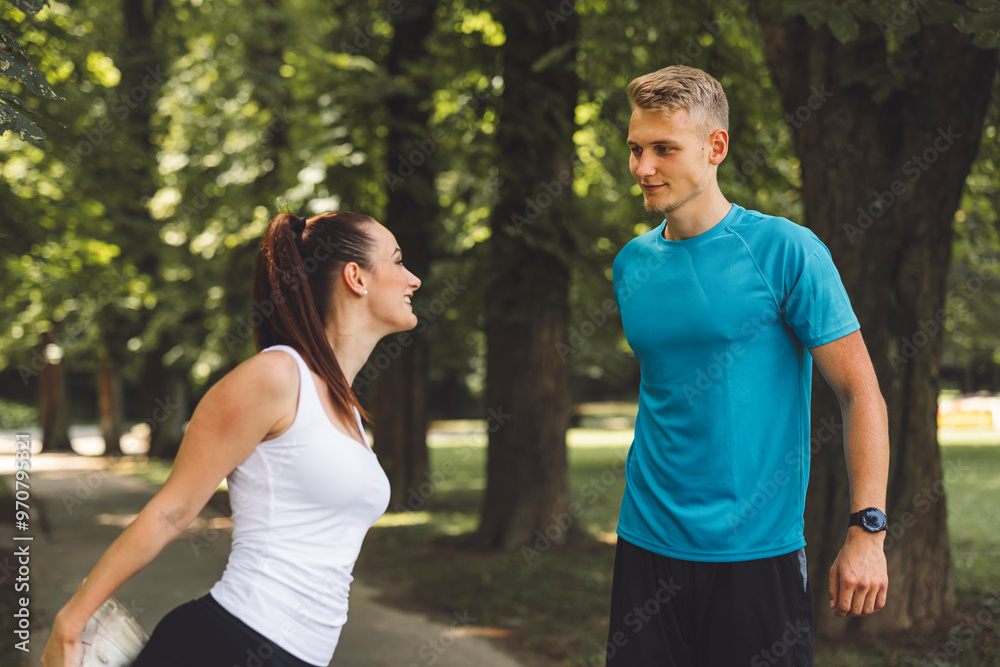 A man and woman in athletic attire are positioned in a starting stance on a path surrounded by trees. The woman is on her knees, while the man is in a crouched position, both ready to race. The scene A man and woman in athletic attire are positioned in a starting stance on a path surrounded by trees. The woman is on her knees, while the man is in a crouched position, both ready to race. The scene