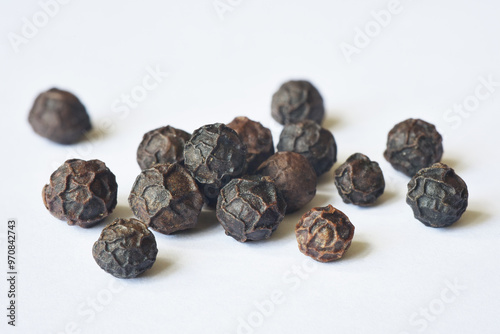 Close up photograph of dry black peppercorns. Food spices for cooking. Macro, details and texture, realistic. Isolated on white background. 