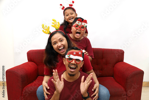 Asian family celebrating Christmas and New Year while sitting on red sofa. Isolated on white background