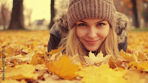 A young woman enjoying autumn by lying in a pile of colorful leaves in a park on a sunny day