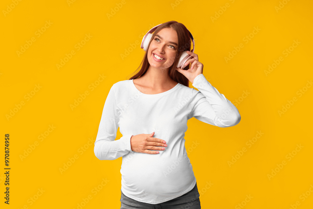 Music In Pregnancy. Smiling Expectant Girl In Headphones Listening To Song Over Pink Background. Studio Shot
