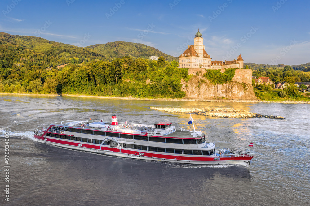 Panorama of Wachau Valley with castle Schonbuhel above the Danube River against tourist boat in Lower Austria, Austria.