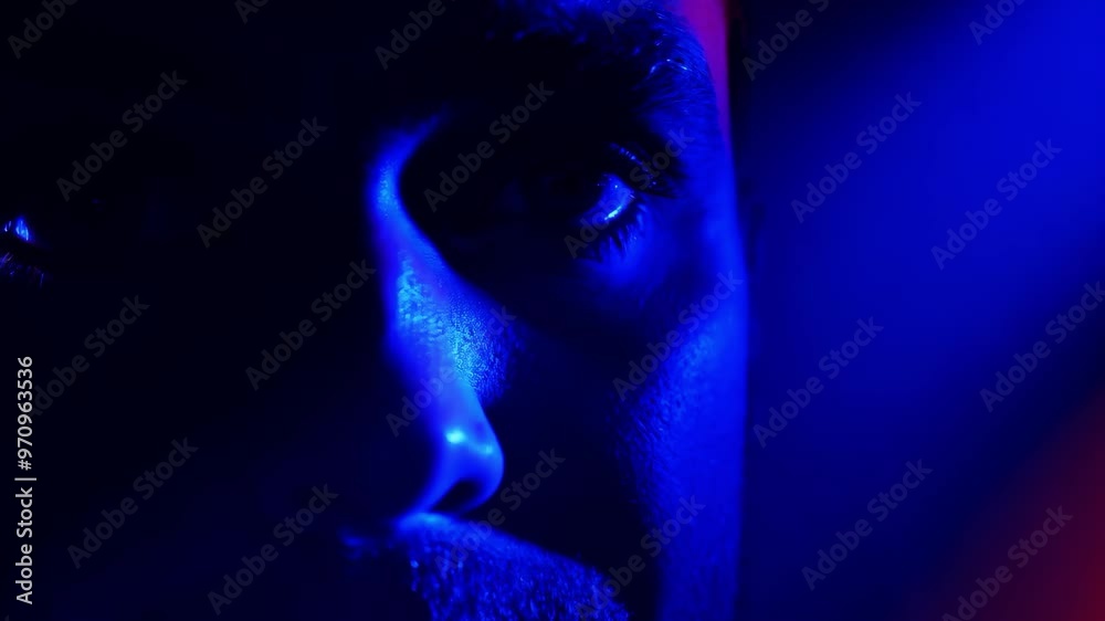 Mysterious blue light illumination on man's face close-up in darkness Mysterious blue light illumination on man's face close-up in darkness
