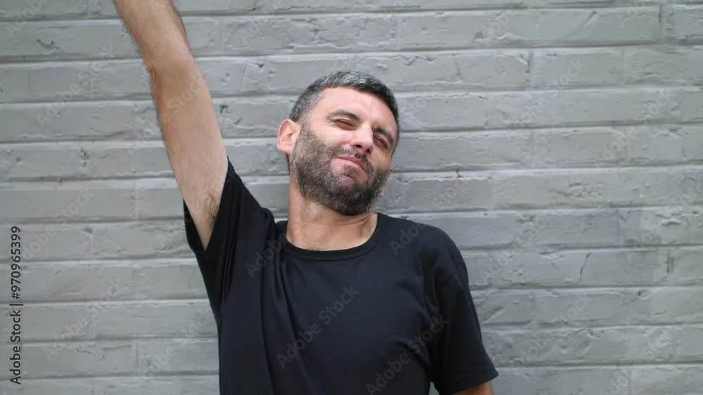 A medium shot of a man stretching his arms, indicating a moment of relaxation or relief. He appears to be letting go of stress and easing his body. A medium shot of a man stretching his arms, indicating a moment of relaxation or relief. He appears to be letting go of stress and easing his body.