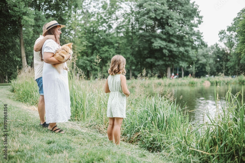 Fototapeta premium Family standing by pond observing water in natural landscape