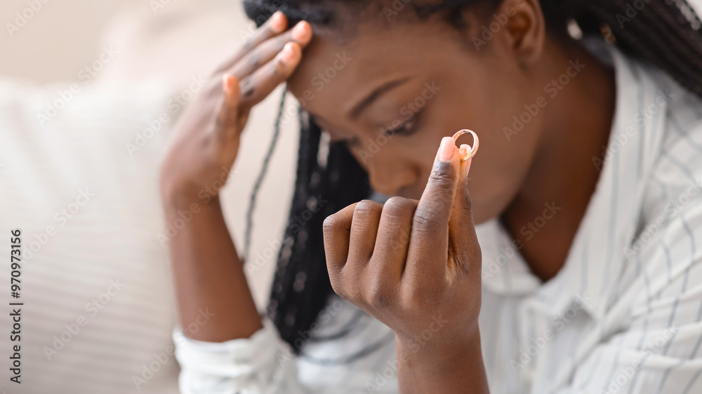 Divorce concept. Gold wedding ring in hand of depressed african american woman, selective focus Divorce concept. Gold wedding ring in hand of depressed african american woman, selective focus