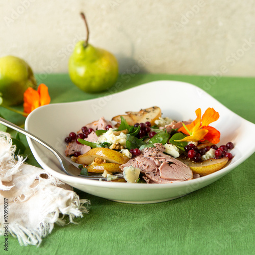bowl of salad with duck breast, pear and blue cheese on table